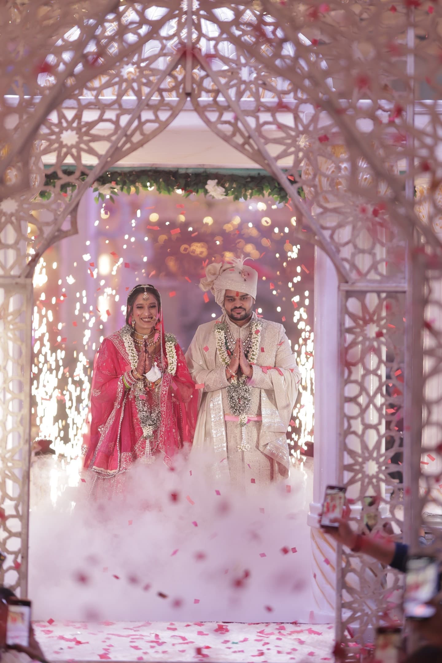 Shagun and Arjun stepping through an ornate white arch at Rajdevam, Agra